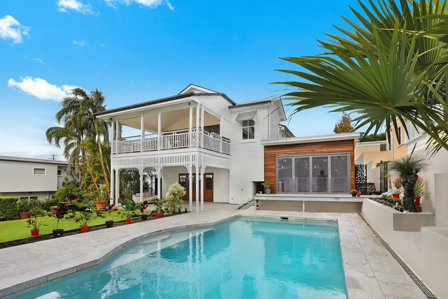 A two-storey house with a covered verandah and a pool